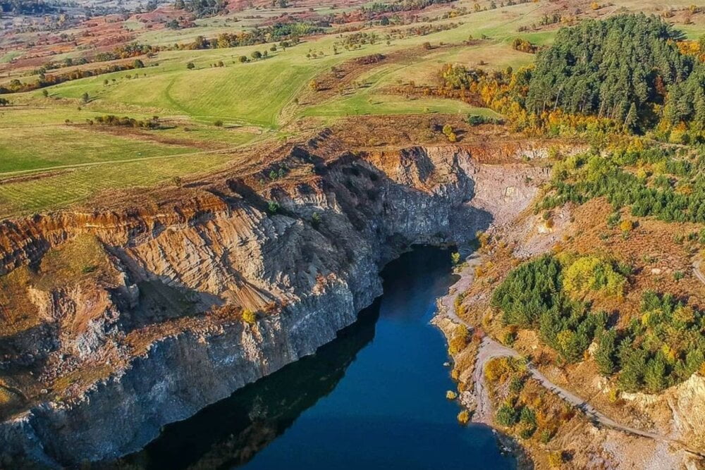 Peisaj spectaculos la Complexul Geologic Racoș, Brașov, incluzând Coloanele de Bazalt și Lacul de Smarald.